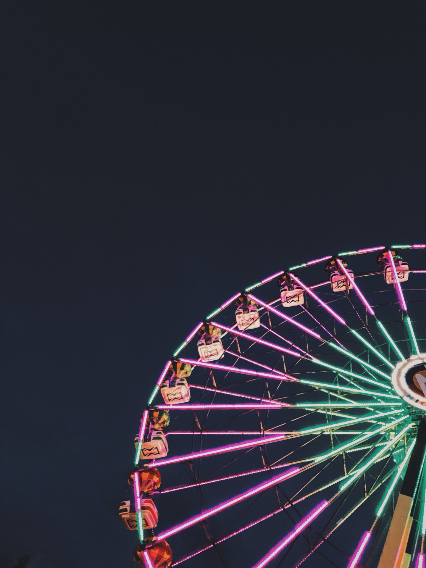 A neon-lit ferris wheel glowing against the night sky