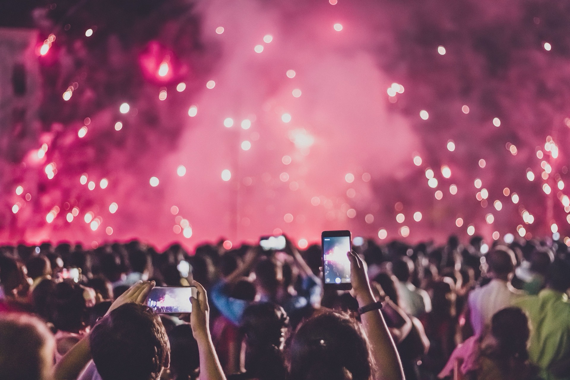 A crowd filming a fireworks display with their phones