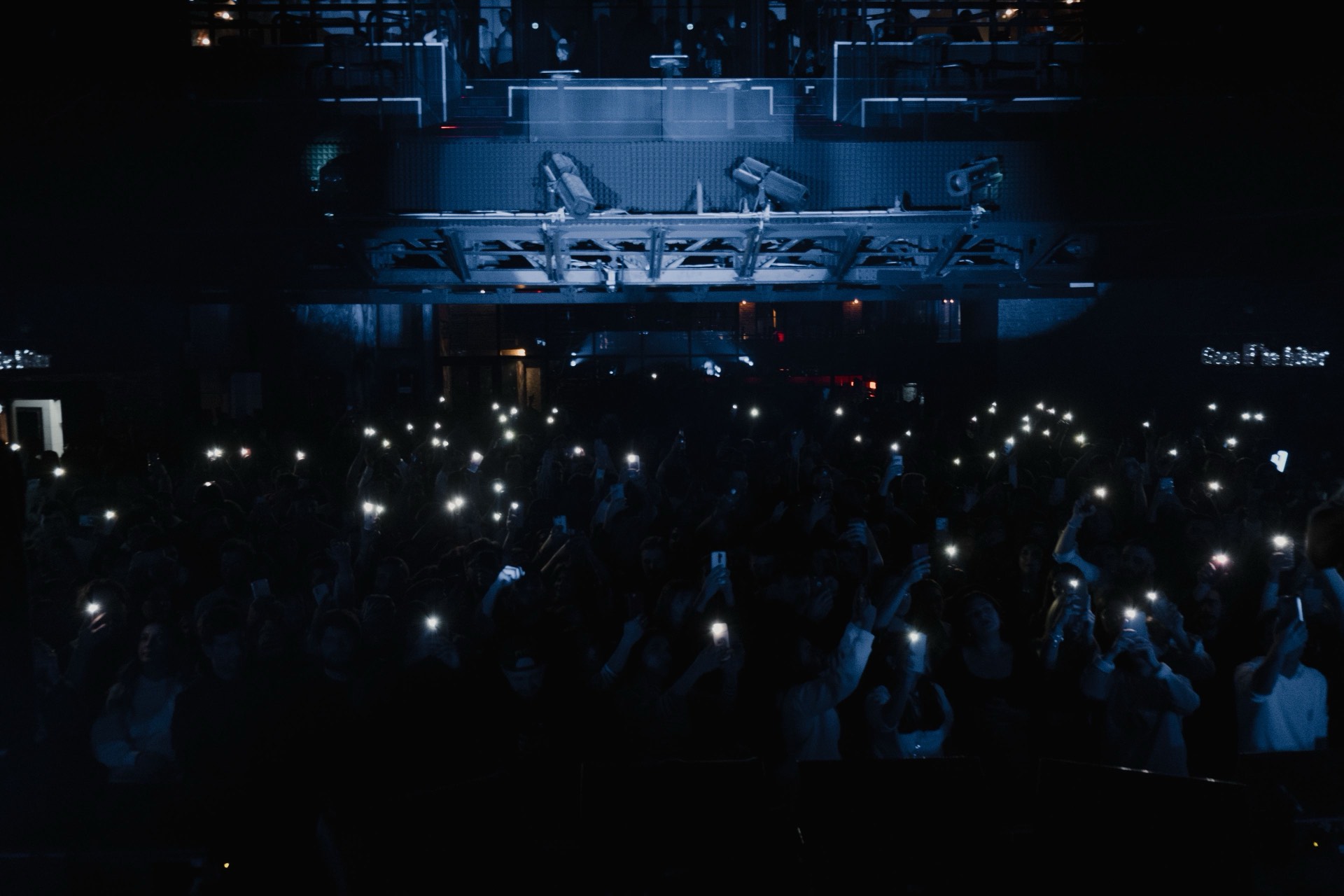 A crowd of phones glowing toward a lit concert stage