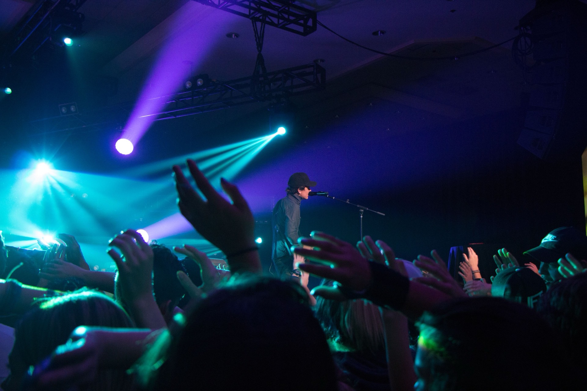 A singer performing on stage under dramatic lights above the crowd